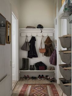 an entryway with shoes and purses hanging on the wall next to a rug