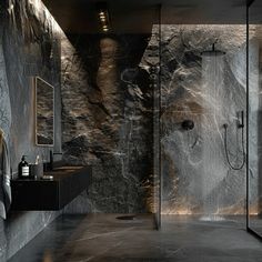 a bathroom with black marble walls and flooring is shown in this image, there are two sinks on the side of the shower