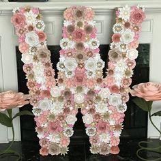 the letter m is made out of flowers and paper machs on a fireplace mantel