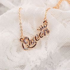 a gold necklace with the word love written in cursive writing on it, sitting on a white lace surface