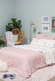 a bedroom with blue walls and pink bedding, white rugs and hanging pictures on the wall