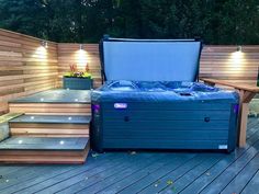 a hot tub sitting on top of a wooden deck next to steps and lights above it