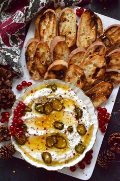 a platter filled with bread, olives and hummus next to other appetizers