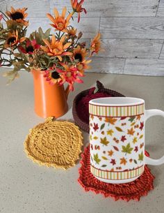 a coffee cup sitting on top of a table next to a vase filled with flowers