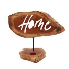 a piece of wood with the word home written in white ink on it, sitting on top of a wooden stand