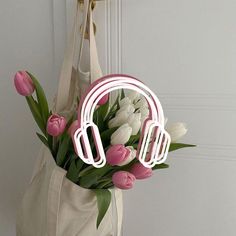 a bouquet of tulips and pink roses in front of a white bag with headphones on it