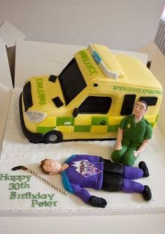 a birthday cake with an ambulance and man laying on the ground