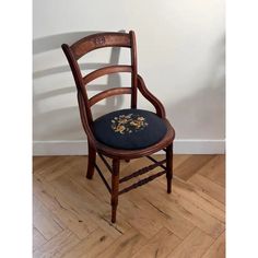 a wooden chair sitting on top of a hard wood floor next to a white wall