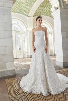 a woman in a white wedding dress standing on a rug with an archway behind her