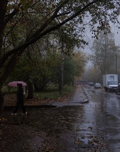 a person with an umbrella is walking down the street in the rain on a rainy day