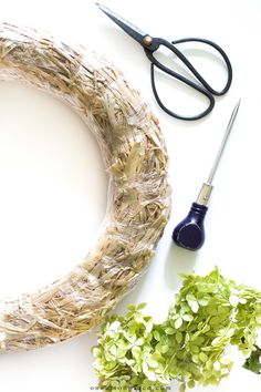 a wreath, scissors and some plants on a table