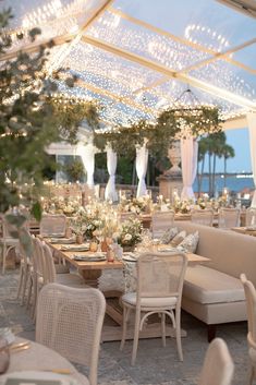 an outdoor dining area with tables, chairs and chandeliers on the roof over looking the water