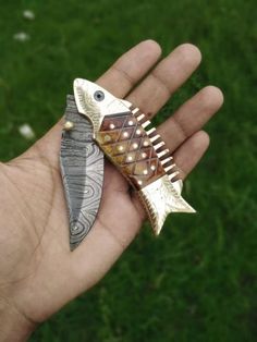 a person is holding two different types of fish brooches in their hand,