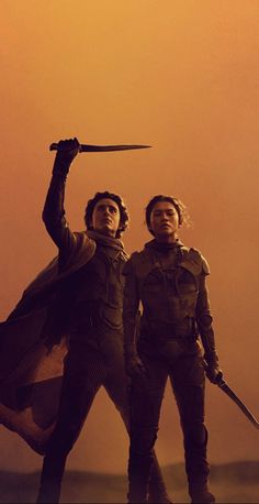 two men holding swords in front of an orange sky