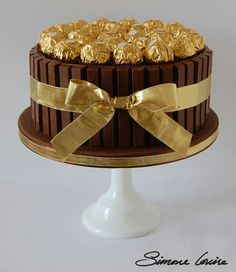 there is a chocolate cake with gold decorations on the top and bottom, decorated with golden ribbons