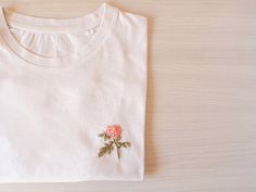 "Hand Embroidered women shirt with a flower. A beautiful t-shirt made of organic cotton. Discover its incredible soft touch and you will never want take it off. T-SHIRT DETAILS The sleeve is short and the neck is ribbed. SIZES: From XS to L (if you are looking for another one, ask me by message). It is an oversized t-shirt. The size of the photos is an S, it is not adjusted so I recommend you use the size you usually use or perhaps one less. The length is up to the hip approximately. You can che Flower T Shirt, Embroidered Designs, T Shirt Flowers, Slogan Tshirt, Customise T Shirt, Inspirational Shirt, Flower Shirt, Women Shirt, Embroidered Tshirt