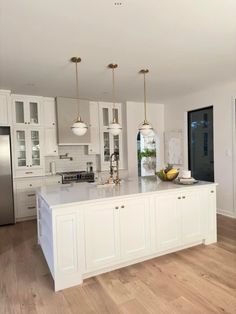 a kitchen with white cabinets and an island in the middle of the room is lit by two pendant lights