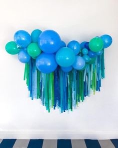 blue and green balloons are hanging on the wall