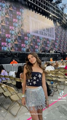 a woman standing in front of a stage wearing a skirt and crop top with stars on it