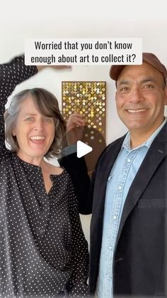 a man and woman standing next to each other in front of a wall with pictures on it