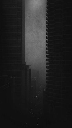 a black and white photo of tall buildings in the fog