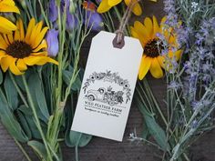 a bunch of flowers that are sitting next to each other on a wooden table with a tag