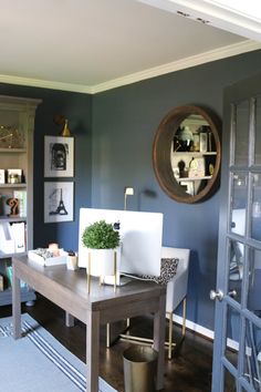 a desk with a laptop on top of it in front of a mirror and door