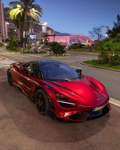 a red sports car is parked on the side of the road in front of palm trees