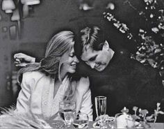 a man and woman sitting at a table with wine glasses