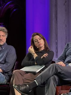 three people sitting in chairs with their arms crossed