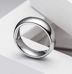 a silver ring sitting on top of a white surface next to a box with the lid open