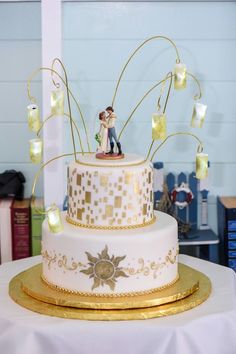 a wedding cake decorated with gold and white frosting, featuring a bride and groom on top