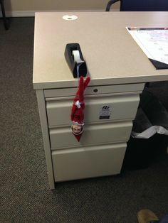 an elf's hat hanging from the handle of a filing cabinet in an office