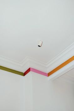 an empty room with white walls and multicolored stripes painted on the ceiling above