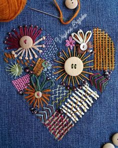 a heart made out of buttons and pins sitting on top of a blue piece of cloth