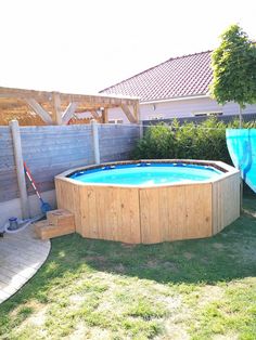 an above ground pool in the backyard with a wooden fence around it and a slide