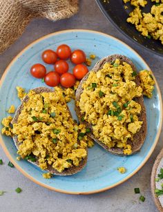 two pieces of bread with eggs and tomatoes on them next to a bowl of cherry tomatoes