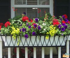 a window box filled with colorful flowers sitting on top of a white rail next to a brick building