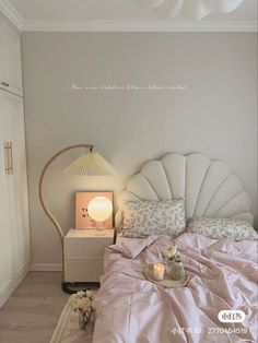 a white bed sitting next to a lamp on top of a table