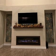 an empty living room with a fireplace and flat screen tv mounted on the wall above it