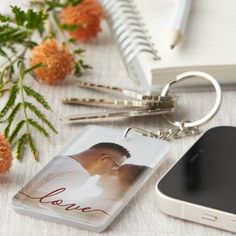 a personalized photo and text keychain next to a cell phone on a table