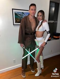 a man and woman dressed up as star wars characters posing for the camera with lightsaben swords