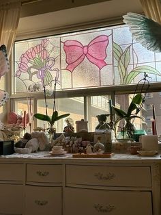 a kitchen counter topped with lots of clutter next to a large stained glass window