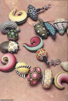 a collection of colorful beads and charms on a pink surface with a butterfly in the middle