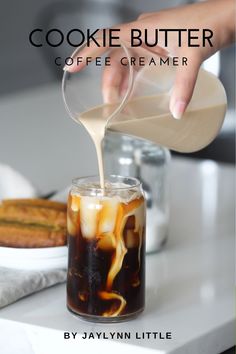 someone pouring coffee into a glass on top of a white counter with cookies in the background