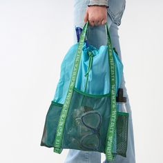 a person holding a mesh bag with the letter b on it and two handles in blue