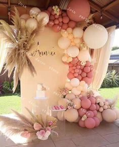 a table topped with lots of balloons next to a wall covered in flowers and palm trees