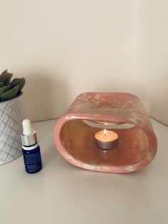 a small candle sits on a table next to a vase with succulents