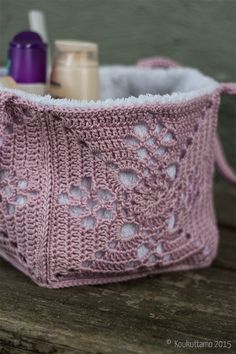 a pink crocheted bag sitting on top of a wooden table