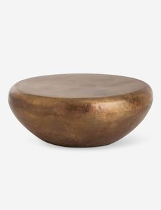 a large metal bowl sitting on top of a white surface with a gold pat finish